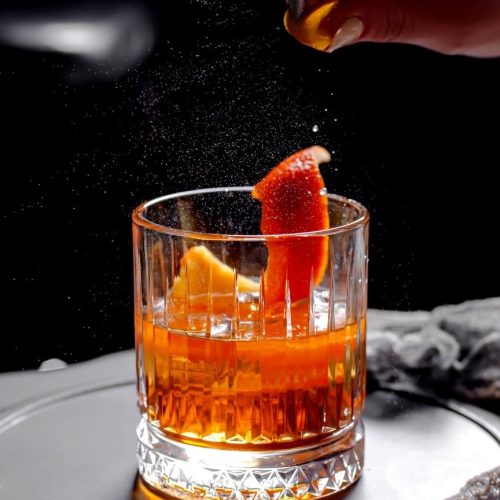 close-up-crystal-viski-glass-with-alcohol-cocktail-garnished-with-orange-zest-min.jpg